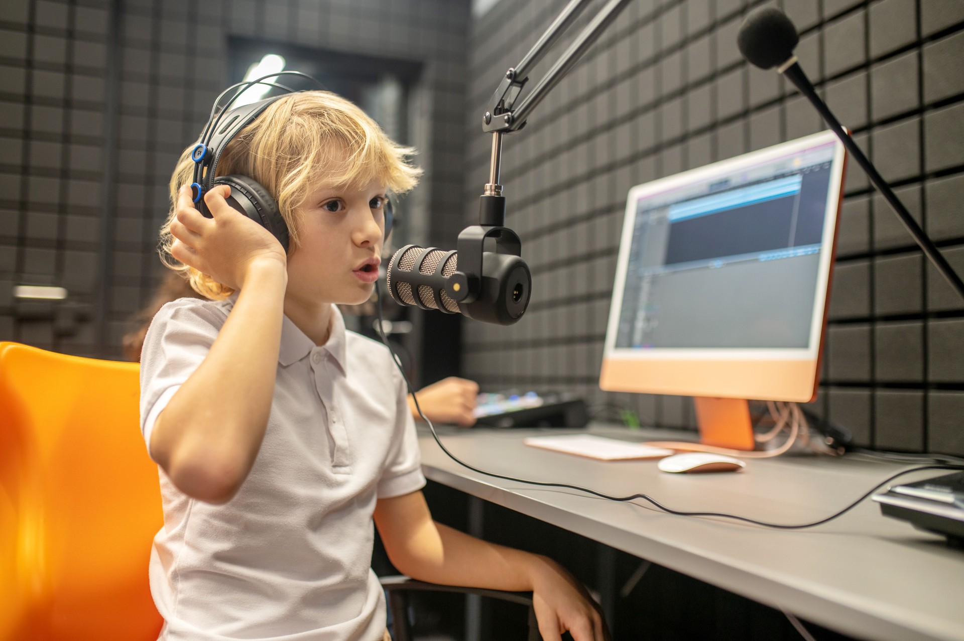 Focused kid broadcasting a program from the radio station